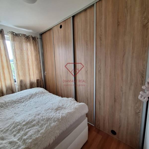 Bedroom in a 3-room apartment with a large built-in wardrobe and curtains on the windows.