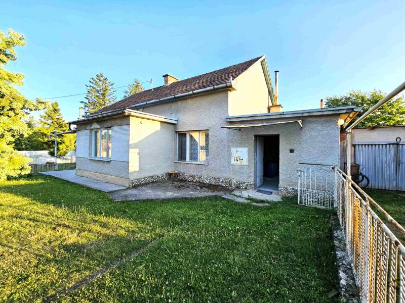 A family house in Kuzmice surrounded by a lawn and trees with a garage on the side.