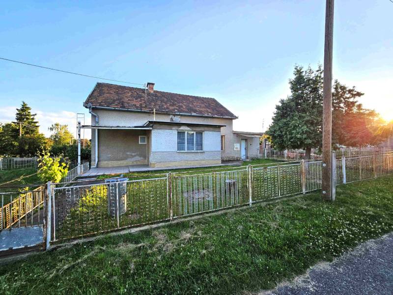A family house in Kuzmice with a grassy yard and fencing on a quiet street.