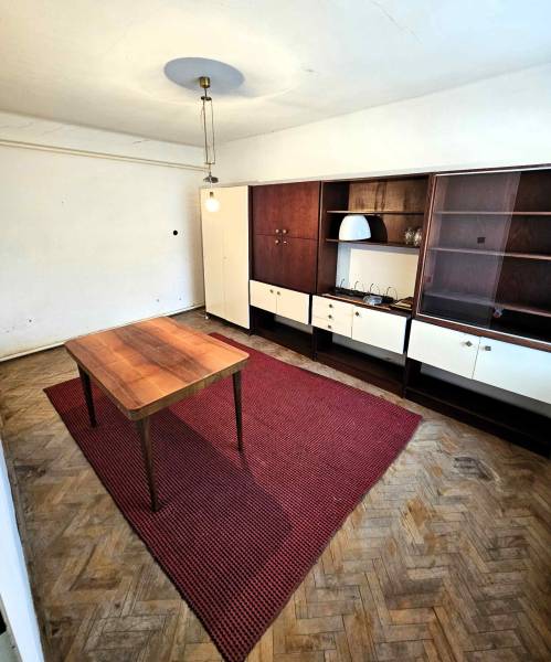 A room with a wooden table, a red carpet, and retro furniture in a family house.
