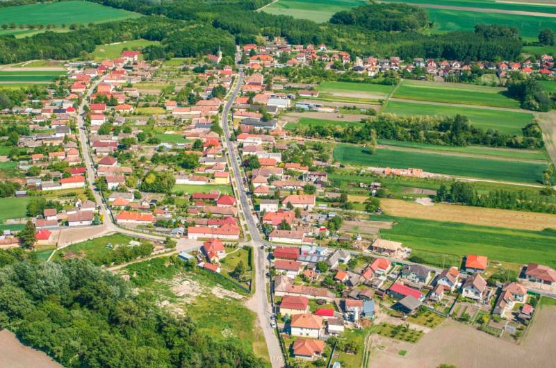 A rural village surrounded by agricultural and forest lands and greenery.