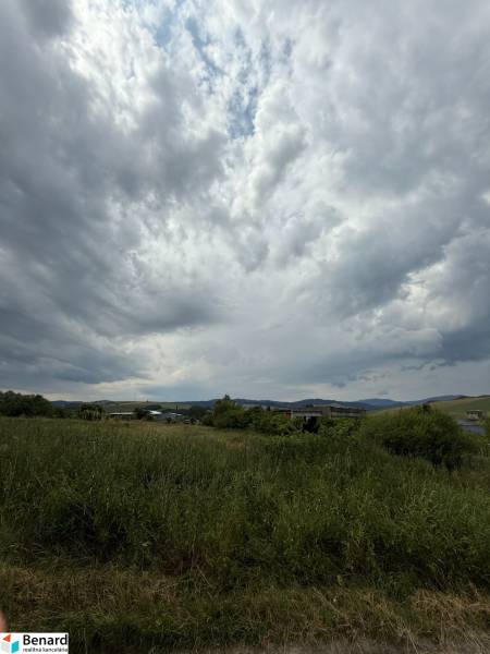 Cloudy sky over green commercial lands in Ľubotín with a visible horizon.