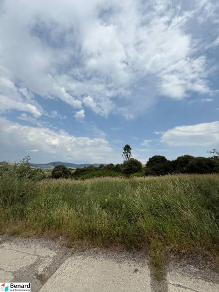 Natural scenery in Ľubotín with commercial land, sky with clouds and green vegetation.