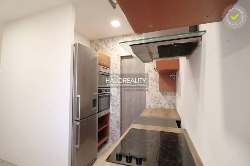 Kitchen with a stovetop, oven, and refrigerator in a family house, bright walls.