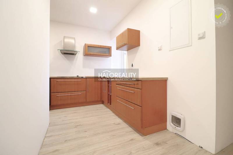 A small kitchen with wooden cabinets and a range hood suitable for a family house.