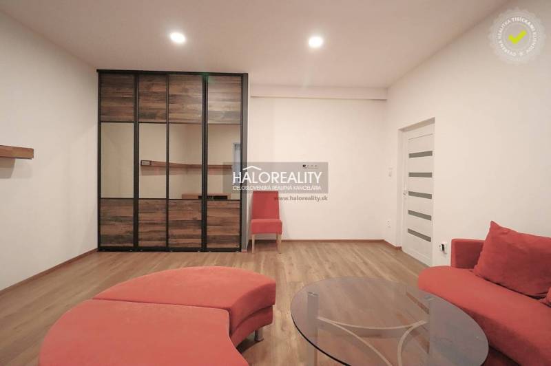 Living room in a family house with a red sofa, wooden floor, and glass table.