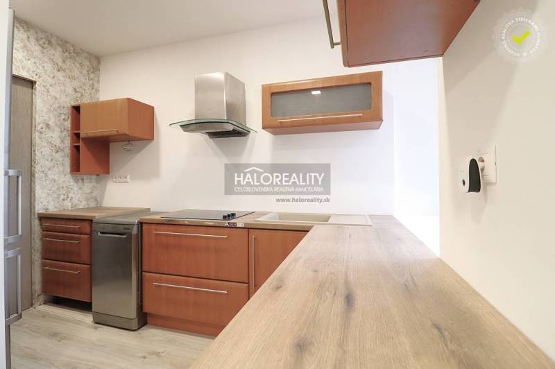A kitchen with appliances, wooden cabinets, and a countertop, all in a family house.
