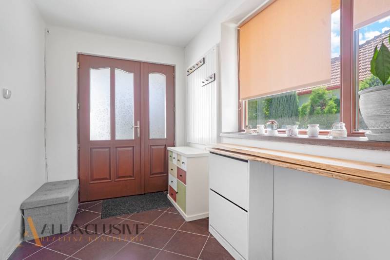 Entrance hall in a family house with wooden doors and a large window with a blind.