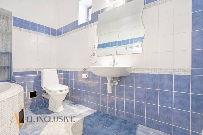 A bathroom in a family house with blue and white tiles and a sink.