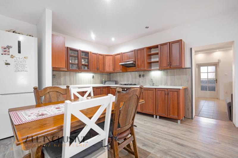 A kitchen in a family house, wooden kitchen unit, dining table and chairs.