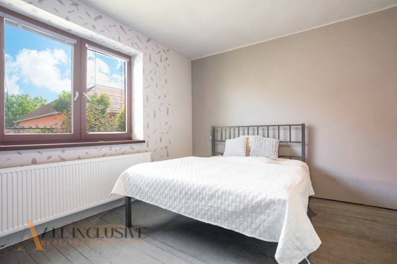 A bedroom in a family house with a metal bed and a large window with a view.