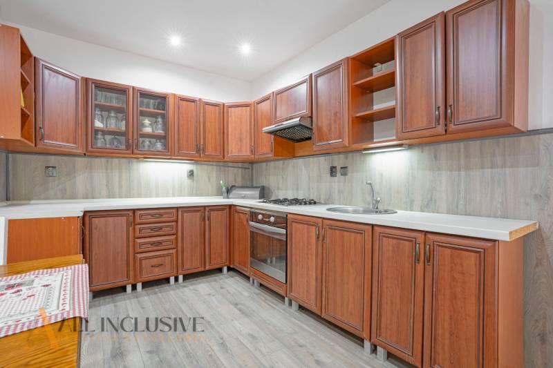 Kitchen in a family house with wooden cabinets and a stove.