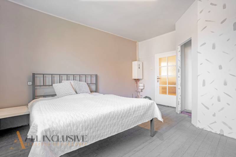 Bedroom with a comfortable bed and a water heater in a family house.