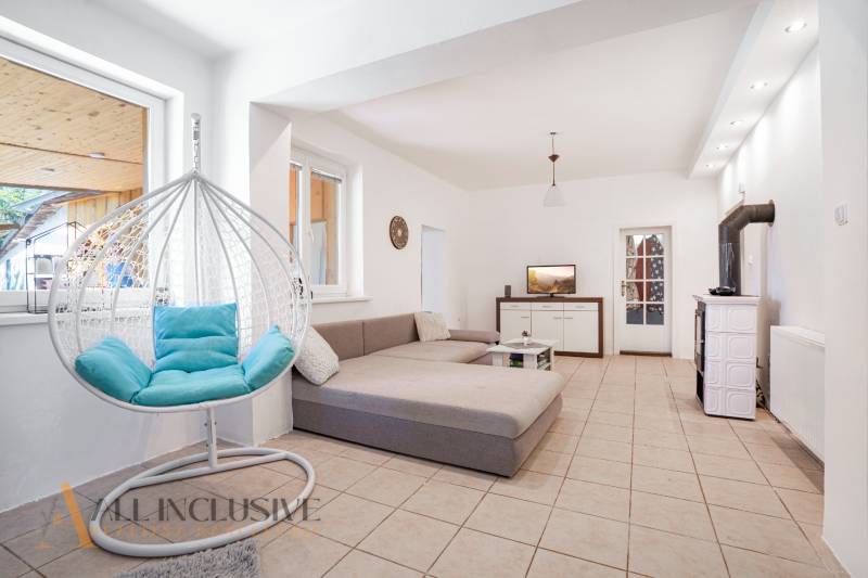 The interior of a family house with a comfortable sofa, a hanging chair, and a tiled stove.
