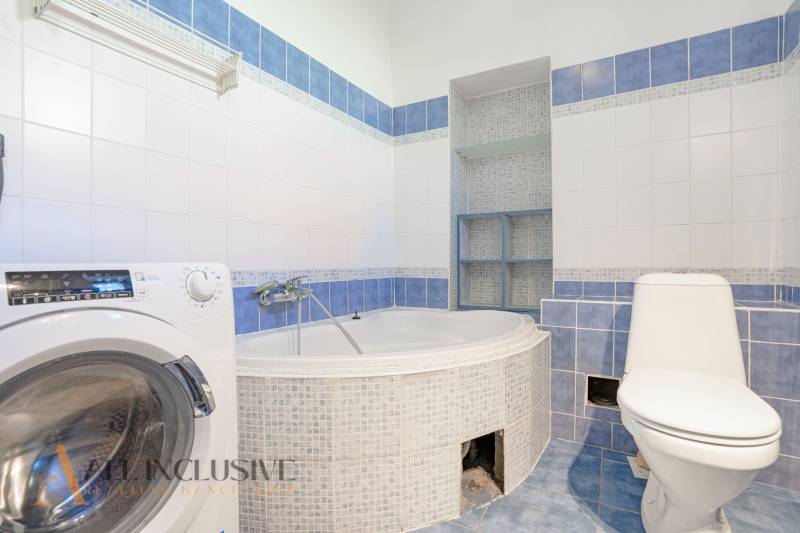 Bathroom in a family house with a shower bath, toilet, and washing machine.