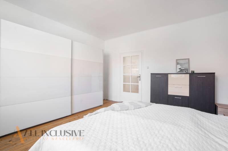 A bedroom in a family house with white cabinets and dark furniture.