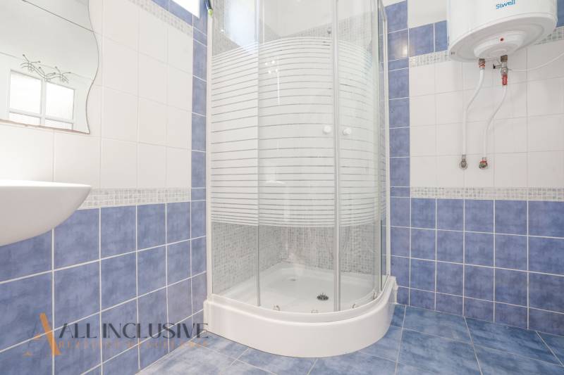 A bathroom with blue and white tiles, a shower corner, and a gas boiler in a family house.