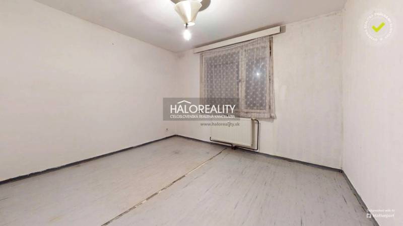 An empty room with light walls and floor and a radiator in a 3-room apartment.