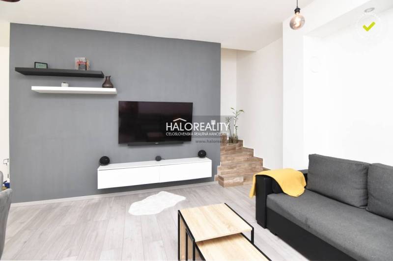 Living room in a family house with a TV on a grey wall, stairs by the wall.