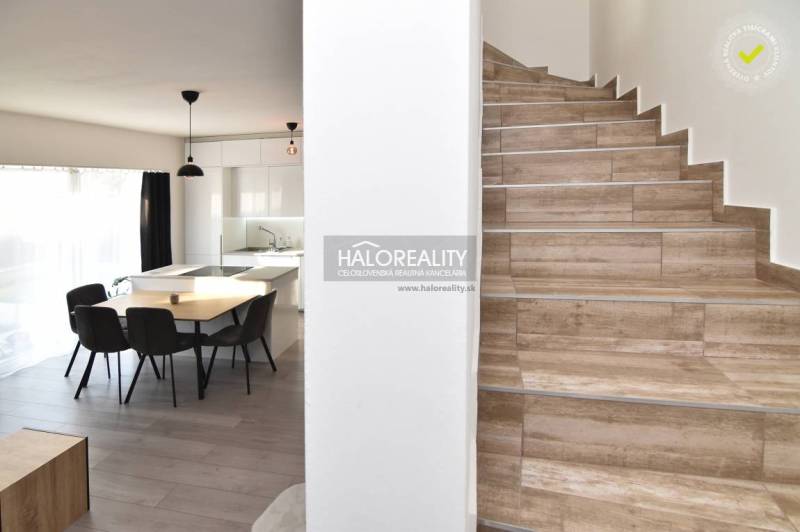 Dining area with staircase in a family house, wooden floors, light furnishings.