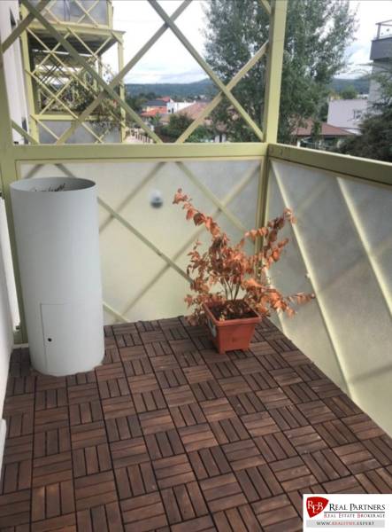 Balcony of a 2-room apartment with plants and wooden flooring, view of the surroundings.