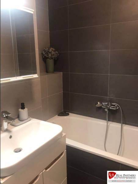 Bathroom in a 2-room apartment with a bathtub, sink, and mirror on the wall.