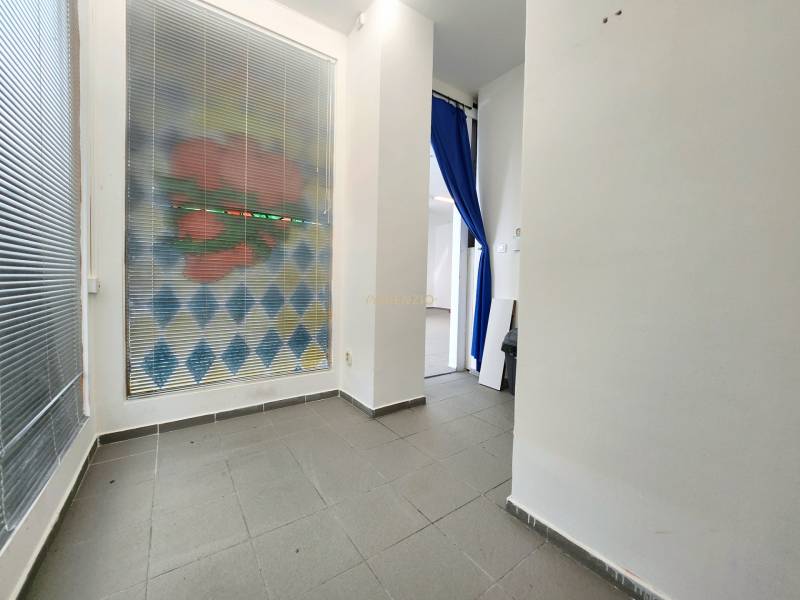 Interior of a commercial space with a tiled floor and a blue curtain.