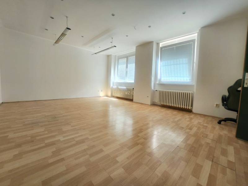 Spacious commercial spaces with wooden flooring and large windows with blinds.