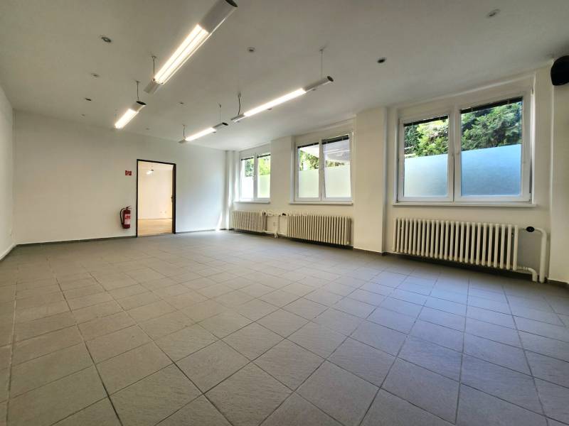 Spacious commercial spaces with windows, radiators, and pendant lighting.