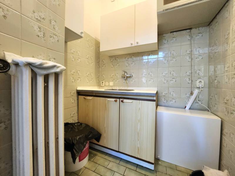 Kitchen corner with a sink, cabinets, and a heater in commercial premises.