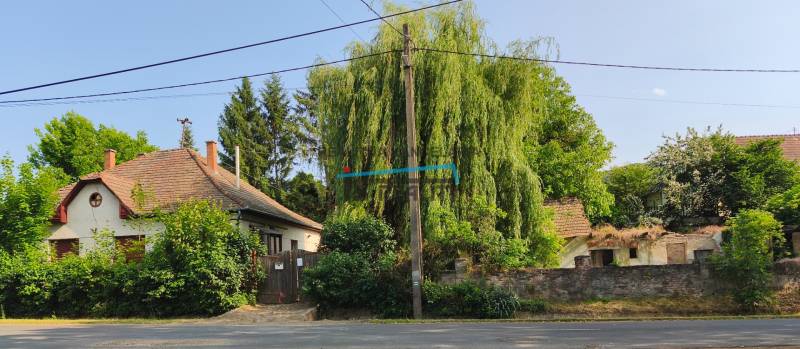 A family house in the town of Hont, surrounded by greenery and trees, next to a fenced garden.