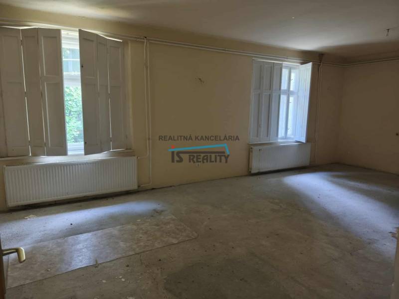 A spacious room with two large windows and radiators in a family house.