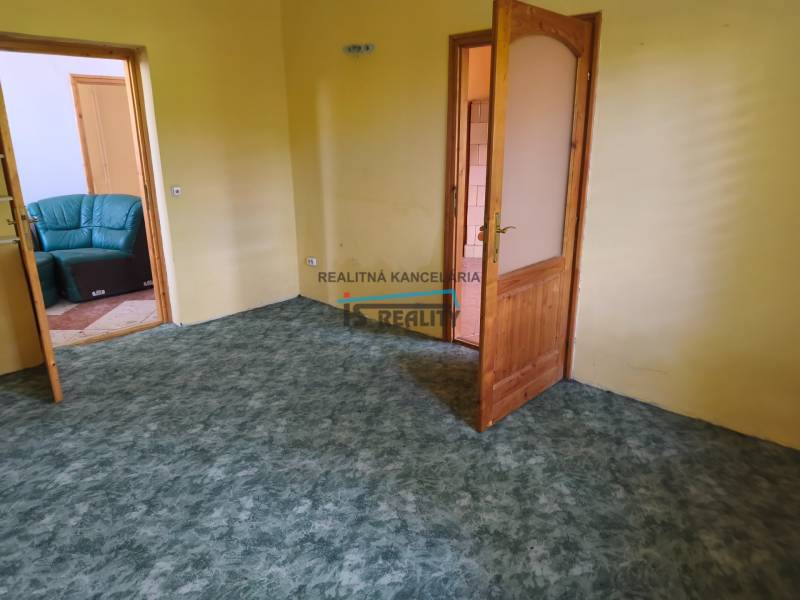 A room in a family house with yellow walls and a green carpet, open doors to the sofa.