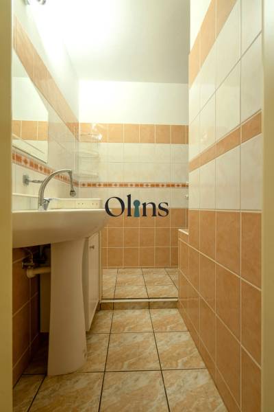 A bathroom with light tiles and a sink in a 2-room apartment.