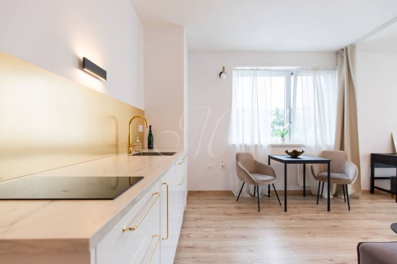 A kitchen with gold accessories and a dining area in a studio apartment.