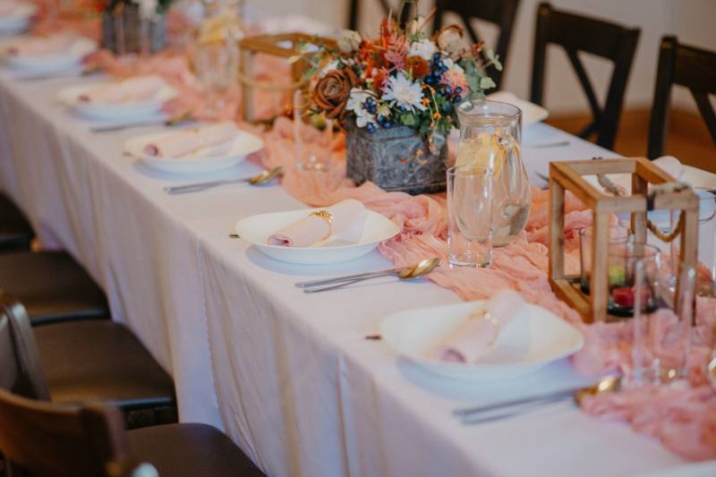 Tables set with decorations and flowers in dining areas, prepared for a festive event.