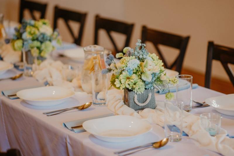 A table in a dining area with decorated plates and floral arrangements.
