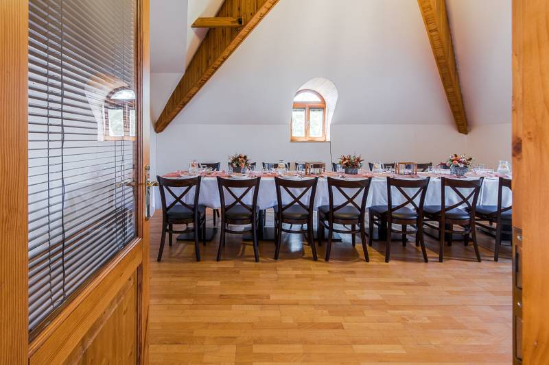 A table in a dining area with place settings and decorations, accessible through glass doors.