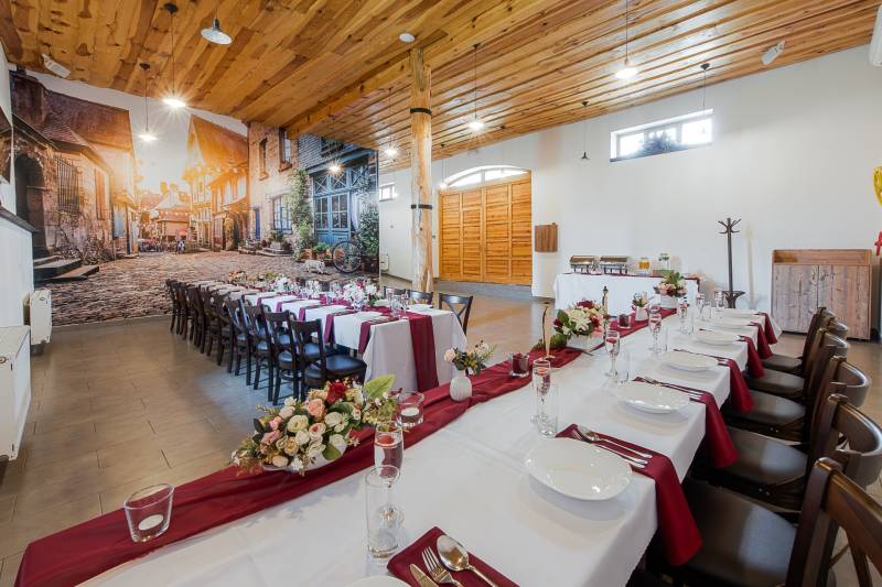 Interior of a gastro space with long tables, flowers, and a large wall mural.