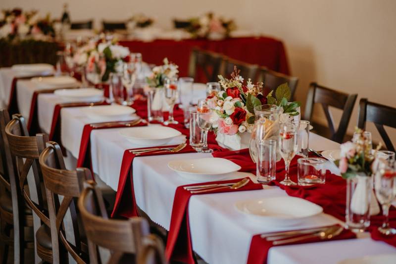 Festively set tables in dining areas with red napkins and floral arrangements.