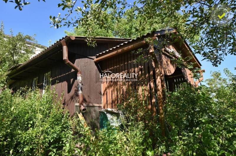 A wooden cottage in the Gardens in Nová Baňa surrounded by dense vegetation and greenery.
