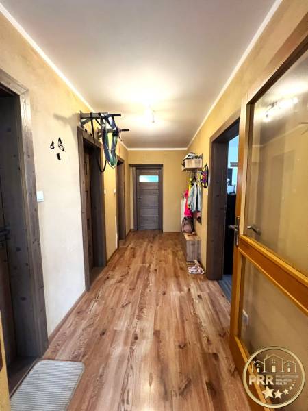 A hallway of a family house with a wooden floor and doors, furnished with coat racks.