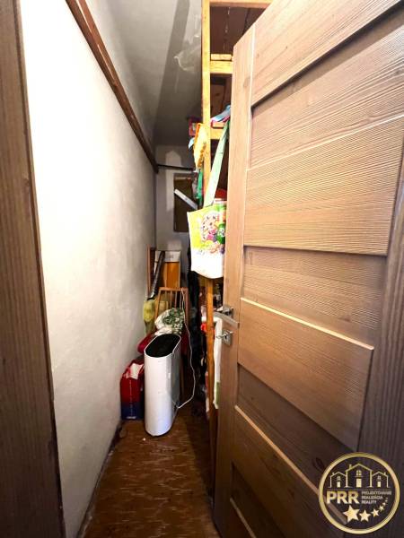A narrow room in a family house with shelves and stored supplies.