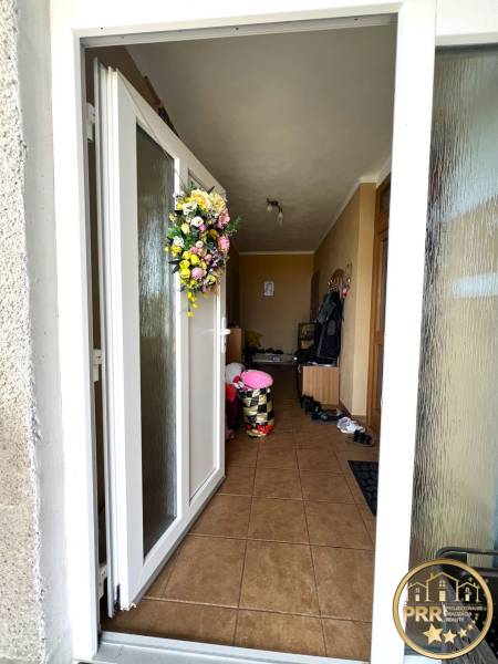 Entrance to a family house with a floral wreath on the door and tiles on the floor.