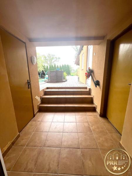 A hallway with stairs and tiles leads to the terrace in a family house.