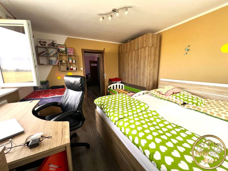 Children's room in a family house with wooden furniture, a bed, shelves, and a desk.