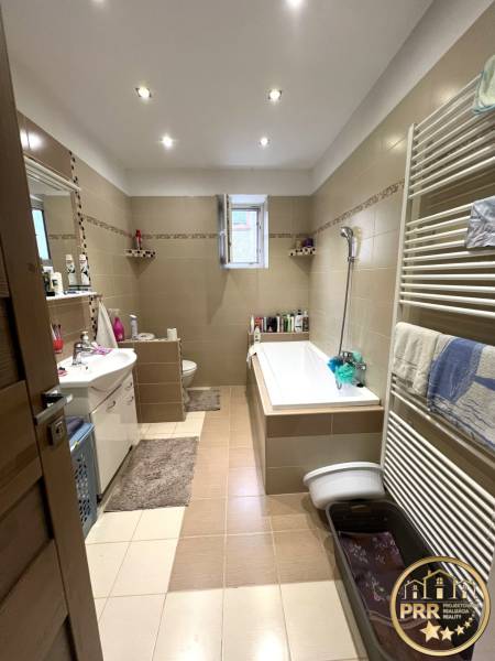 A bathroom in a family house with a bathtub, a sink, and a window.
