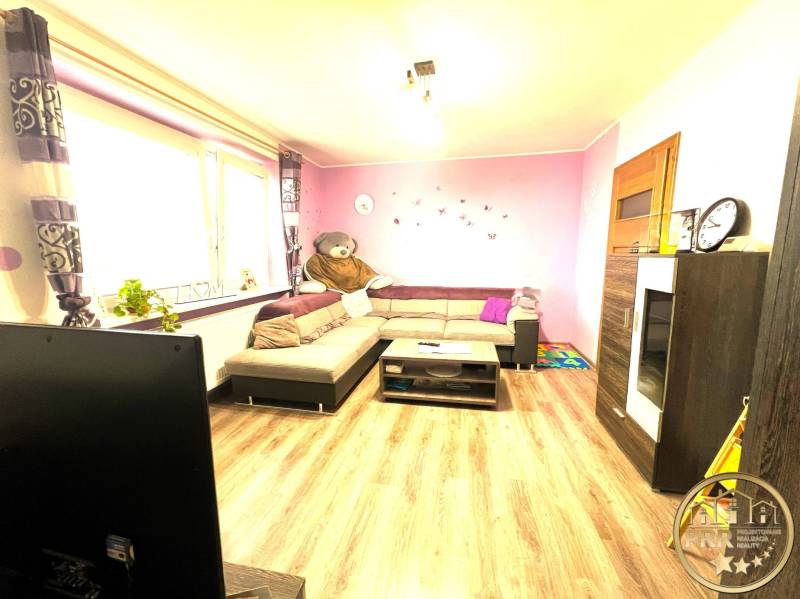 Living room in a family house with a corner sofa, decorations, and a window with flowers.