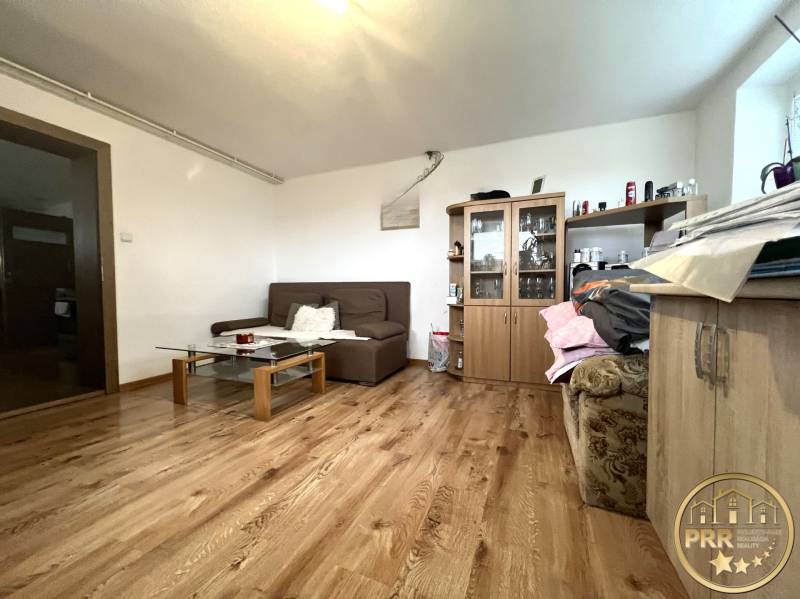 Living room in a family house with wooden flooring, a sofa, and a cabinet.