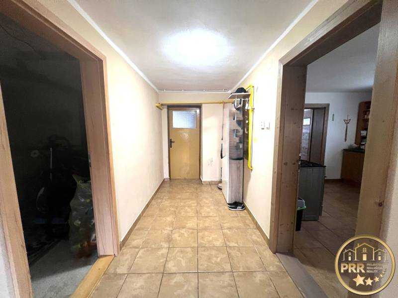 A hallway in a family house with two doors and tiled flooring.